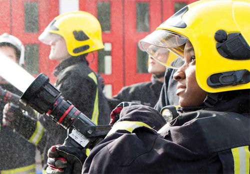 Young people on LIFE course using hoses with firefighter supervising.